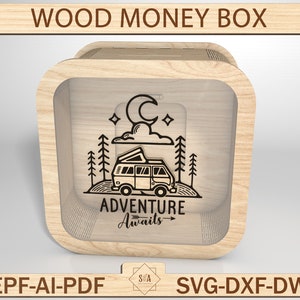 May include: A wooden money box with a cutout design of a camper van, trees, a moon, and clouds. The text "ADVENTURE Awaits" is below the design.
