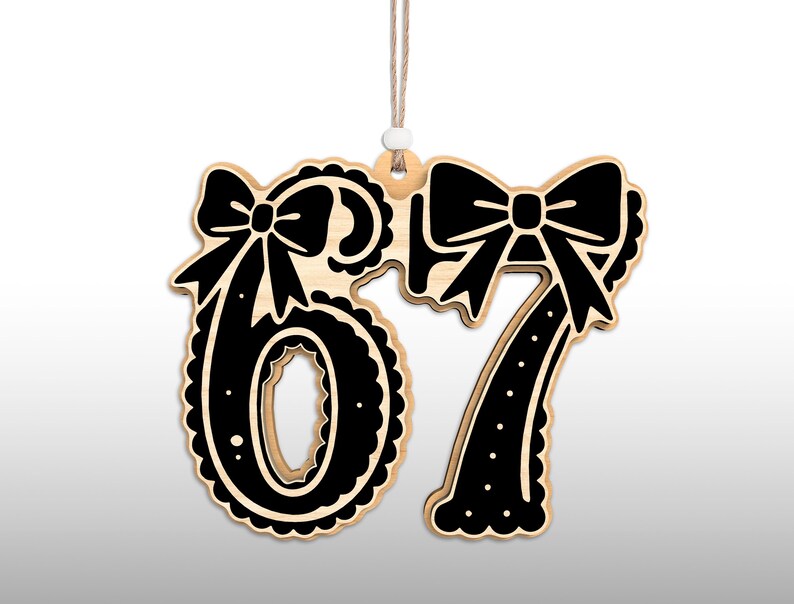 May include: Wooden ornament featuring the numbers 67 in a black and natural wood color scheme. Each number is adorned with a decorative bow. The ornament hangs from a natural twine string with a small white bead.