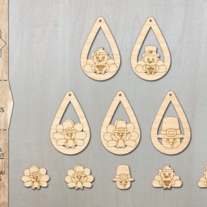 May include: Six laser cut wooden turkey earring designs. Each earring features a turkey wearing a pilgrim hat. The designs include a turkey with a full body, a turkey with just the head and hat, and a turkey with just the head and hat with a feather design.