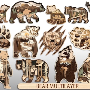 May include: A collection of twelve multilayered wooden bear-shaped wall art pieces featuring intricate laser-cut forest, mountain, and wildlife scenes. The set includes various bear silhouettes, paw prints, and a bear head, labelled BEAR MULTILAYER.