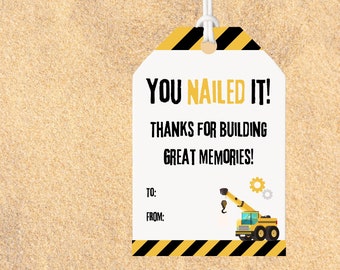May include: A white tag with black and yellow stripes, a construction crane graphic, and the text "YOU NAILED IT! THANKS FOR BUILDING GREAT MEMORIES!"  The tag has blank lines for "TO:" and "FROM:".