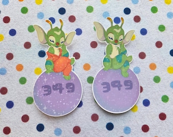 May include: Two stickers featuring a green alien character with large ears and orange overalls. The alien sits atop a purple sphere with the number "349" printed on it. The background is white with colorful polka dots.