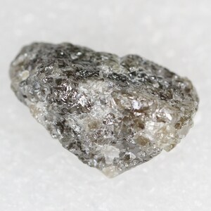 Puede incluir: Un cristal de diamante en bruto, gris y de forma ligeramente irregular.