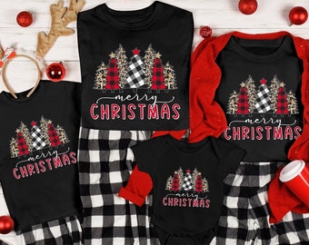 May include: A collection of black short-sleeved shirts and a black baby bodysuit, each featuring a graphic of stylized Christmas trees in red plaid, black and white buffalo check, and leopard print, with the text Merry Christmas in red.