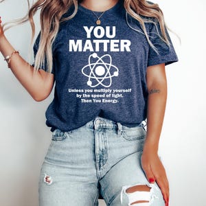 May include: Navy blue t-shirt with the white text "YOU MATTER" above a graphic of an atom. Below the atom graphic is the text "Unless you multiply yourself by the speed of light. Then You Energy."