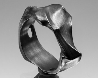 May include: A silver ring with a unique, abstract, and organic design. The ring is made of metal and has a brushed finish.