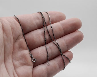 Puede incluir: Un collar de cadena negro con cierre de mosquetón.