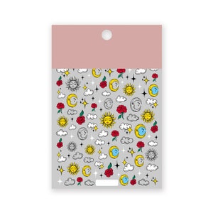 K&ouml;nnte beinhalten: Ein Bogen Aufkleber mit einem himmlischen Thema. Die Aufkleber zeigen Illustrationen von Sonne, Mond, Sternen, Wolken und roten Rosen auf grauem Hintergrund. Die Oberseite des Bogens ist rosa mit einem Loch.