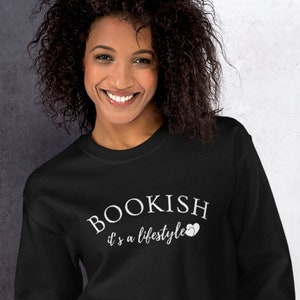 Puede incluir: Una sudadera negra con texto blanco que dice "BOOKISH it's a lifestyle" con un peque&ntilde;o icono de coraz&oacute;n.