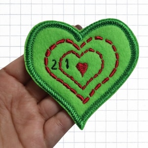 May include: Green felt heart-shaped patch with red embroidered hearts and the number "21" in the center.