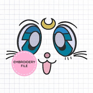 Puede incluir: Un archivo de bordado que muestra una cara de gato estilizada con grandes ojos azules, una luna creciente amarilla en la frente, una pequeña nariz rosa y la lengua fuera. El diseño incluye bigotes negros y un círculo rosa con el texto EMBROIDERY FILE.