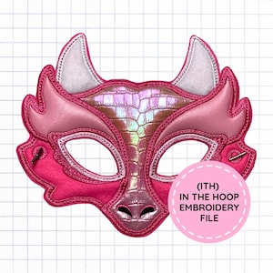 May include: A pink dragon-shaped mask featuring iridescent, textured scales on the forehead and nose, white felt-like inner ears, and embroidered edges. A circular pink label on the bottom right reads (ITH) IN THE HOOP EMBROIDERY FILE.