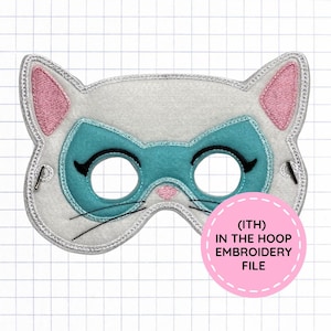May include: A white felt cat mask with pink inner ears, a teal eye mask area, black embroidered eyelashes, and black whiskers. The mask features silver metallic stitching along the edges and includes a pink circular label with the text (ITH) IN THE HOOP EMBROIDERY FILE.