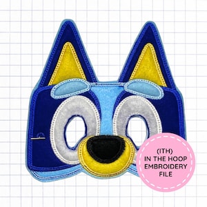 May include: A blue felt mask featuring a cartoon dog design with yellow inner ears, light blue eyebrows, white eye patches, and a yellow snout with a black nose. A pink circular label reads (ITH) IN THE HOOP EMBROIDERY FILE.