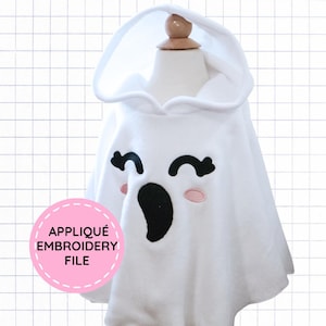 May include: A white hooded poncho featuring an embroidered ghost face with black curved eyes, a black oval mouth, and small pink oval cheeks. A pink circular badge on the lower left displays the text APPLIQUÉ EMBROIDERY FILE in black lettering.