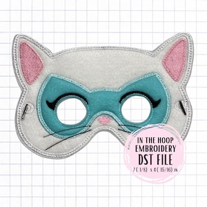 以下が含まれることがあります： ピンクの内耳とターコイズのアイマスクが付いた、白い猫の形をしたマスク。マスクには黒い目の輪郭とひげがあり、シルバーのトリムが付いています。「IN THE HOOP EMBROIDERY DST FILE」というテキストが表示されます。マスクのサイズは18.1 x 12.5 cmです。