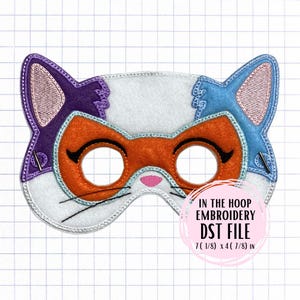 Könnte beinhalten: Eine katzenförmige Schlafmaske in Weiß, Orange, Lila und Blau. Die Maske hat gestickte Details, einschließlich geschlossener Augen und Schnurrhaare. Der Text "IN THE HOOP EMBROIDERY DST FILE" ist sichtbar, zusammen mit den Maßen 18.1 x 12.4 cm.