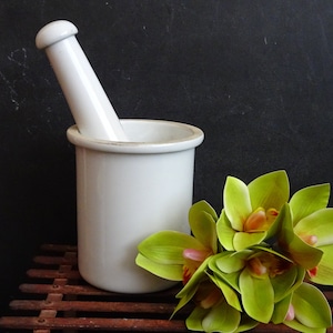 Peut inclure: Mortier et pilon en céramique blanche avec un arrangement de fleurs d'orchidées vertes sur une surface en bois.