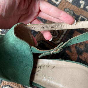 May include: Green suede heeled sandals with a buckle closure. The insole is labeled "Zapat" and the sole has the numbers "7B 2422 15".