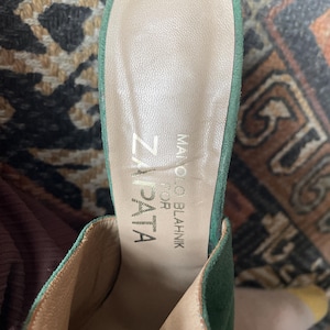 May include: Green suede heeled mules with a light brown leather insole. The insole is labeled "Manolo Blahnik for Zapata"