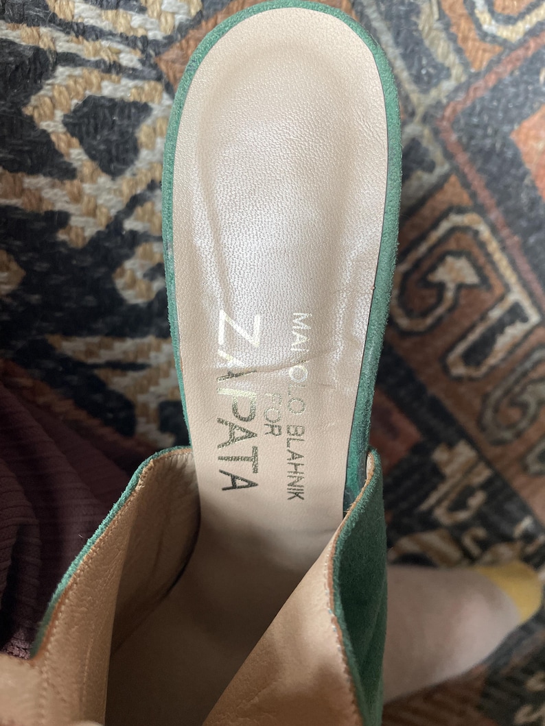 May include: Green suede heeled mules with a light brown leather insole. The insole is labeled "Manolo Blahnik for Zapata"