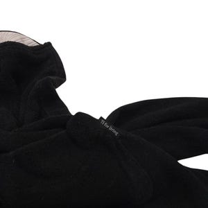 Puede incluir: Una prenda negra con capucha y superficie suave y texturizada. Una peque&ntilde;a etiqueta de tela negra est&aacute; unida al lateral, con el texto blanco Y's for living. El interior de la capucha est&aacute; forrado con una tela clara con finas rayas verticales.