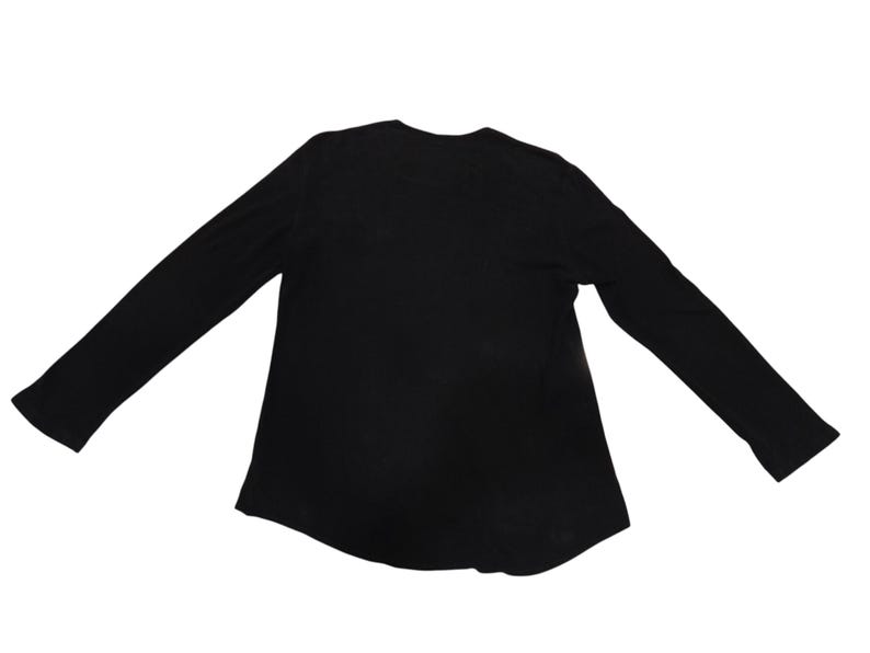 Puede incluir: Una camiseta negra de manga larga con un cuello redondo sencillo y un dobladillo recto. La prenda se presenta sobre un fondo blanco liso, destacando su dise&ntilde;o sencillo, mangas largas y una confecci&oacute;n b&aacute;sica para el uso diario.