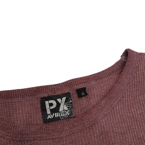May include: A mauve thermal knit long-sleeve shirt with a ribbed crew neckline. A black rectangular label is sewn inside the collar featuring the white text PX AVIREX. A smaller black tag next to it indicates the size as XL.