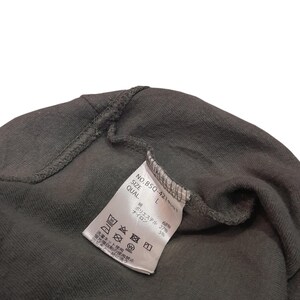 May include: Close-up of a dark gray garment with a white tag. The tag displays text including "NO.BSQ-4211", "SIZE L", and fabric composition percentages. Washing instructions are also visible.