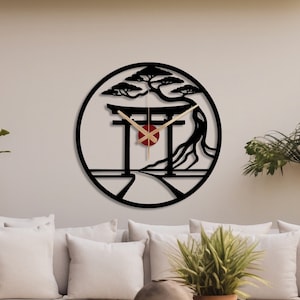 May include: Black and white wall clock with a Japanese-inspired design featuring a torii gate, a tree, and a red circle in the center. The clock is hanging on a white wall.