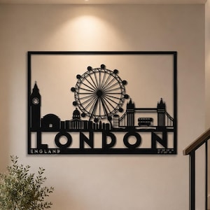 May include: A black metal wall art piece featuring a silhouette of the London skyline, including Big Ben, the London Eye, and Tower Bridge. The word LONDON is cut out in large capital letters at the bottom, with ENGLAND and coordinates below.