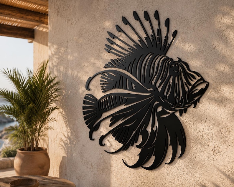 Puede incluir: Una pieza de arte mural de metal negro con forma de pez le&oacute;n, que presenta detalles recortados intrincados que definen las aletas espinosas, la cola fluida y los rasgos faciales distintivos del pez, montada sobre una pared texturizada.