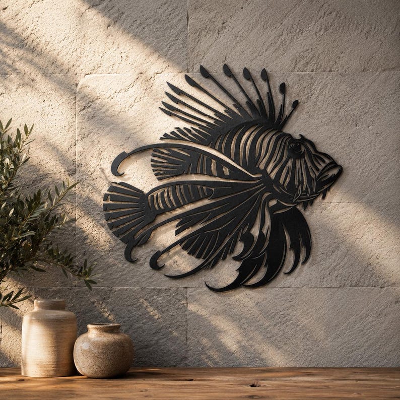 Puede incluir: Una pieza de arte mural de metal negro con forma de pez le&oacute;n, que presenta intrincados recortes que definen las aletas espinosas, las branquias y la estructura corporal del pez. La silueta es plana y oscura, contrastando con la pared de piedra.