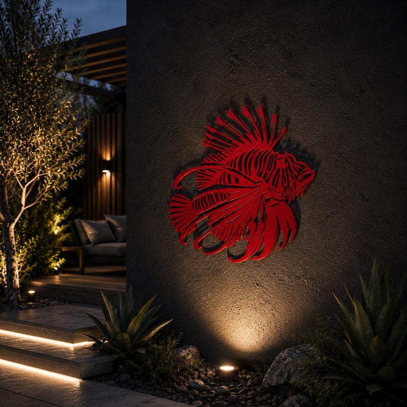 Puede incluir: Una pieza de arte mural de metal rojo vibrante con forma de pez le&oacute;n, que presenta intrincados detalles recortados que definen sus aletas, espinas y estructura corporal. La escultura est&aacute; montada en una pared exterior oscura y texturizada.