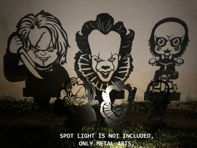K&ouml;nnte beinhalten: F&uuml;nf schwarze Metallsilhouetten von Horrorfilmfiguren, darunter Pennywise der Clown, Chucky und Jigsaw, an einer Wand montiert. Der Text "SPOT LIGHT IS NOT INCLUDED, ONLY METAL ARTS." ist unter den Silhouetten gedruckt.