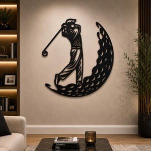 Puede incluir: Una pieza de arte mural de metal negro que presenta la silueta de un golfista en posici&oacute;n de swing. El golfista est&aacute; situado dentro de un gran dise&ntilde;o en forma de media luna lleno de un patr&oacute;n repetitivo de recortes circulares.