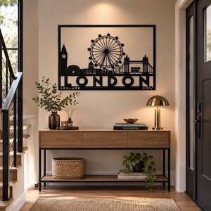 May include: A black metal wall art piece featuring a silhouette of the London skyline, including Big Ben, the London Eye, and Tower Bridge, with the text LONDON ENGLAND printed below. The design is rectangular with a thin black frame border.