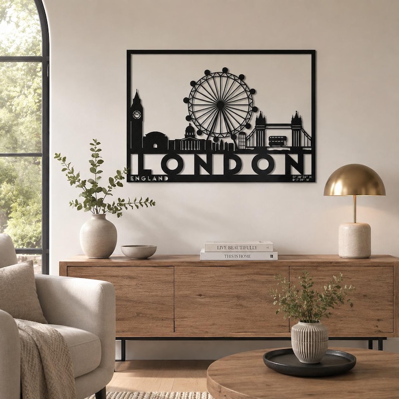 May include: A black metal wall art piece featuring a silhouette of the London skyline, including Big Ben, the London Eye, and Tower Bridge. The word LONDON is cut out in large capital letters at the bottom, with the word ENGLAND underneath.