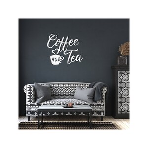 Puede incluir: Arte de pared blanco con las palabras "Coffee and Tea" en fuente cursiva, con un coraz&oacute;n y un s&iacute;mbolo de taza de caf&eacute;. El arte est&aacute; montado en una pared azul oscuro sobre un sof&aacute; con un patr&oacute;n geom&eacute;trico en blanco y negro.