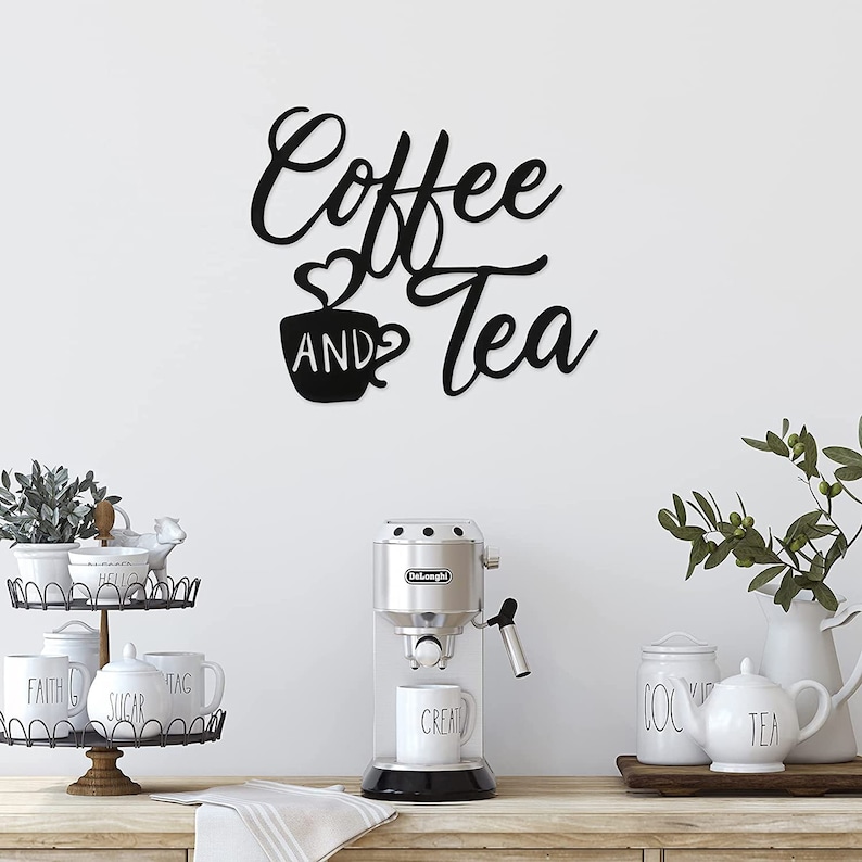 Puede incluir: Arte de pared de metal negro con las palabras "Coffee and Tea" en fuente cursiva, con un gr&aacute;fico de taza de caf&eacute;. Una cafetera, tazas y fuentes para servir est&aacute;n sobre una encimera de madera.