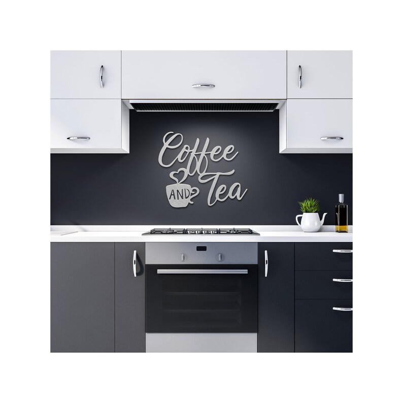 Puede incluir: Un letrero de metal para pared que dice "Coffee AND Tea" en una fuente cursiva, con un s&iacute;mbolo de coraz&oacute;n y un gr&aacute;fico de taza de caf&eacute;. El letrero est&aacute; montado en una pared gris oscuro en un entorno de cocina, encima de una estufa y un horno.