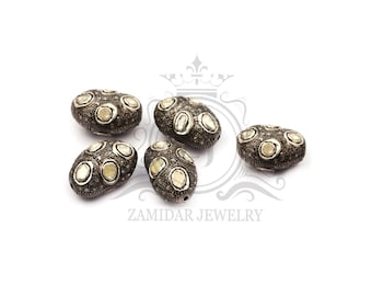 May include: Five oval-shaped silver beads with white gemstones set into the surface. The beads are scattered on a white background.