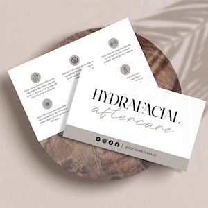 May include: Two white cards with the words "HYDRAFACIAL aftercare" in black and gray. The cards have aftercare instructions and social media icons. The cards are on a wooden surface.