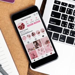 May include: A smartphone displaying a social media profile for a beauty lounge. The profile includes a pink and white color scheme, a logo, a bio, and a grid of nine images. The text on the screen reads "Beauty lounge", "Add Your Bio", "Add Your Description", "www.yourwebsitename.com", and "TITTLE".