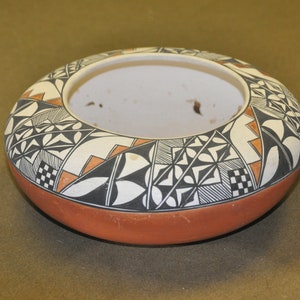 Könnte beinhalten: Eine traditionelle indianische Töpferei-Schale mit einem geometrischen Muster in Schwarz, Weiß und Orange. Die Schale ist aus Ton gefertigt und hat eine abgerundete Form.
