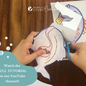 May include: A person is cutting out a paper fish with scissors. The fish is part of a Bible Story Creative craft project. The image includes text that says "Watch the FULL TUTORIAL on our YouTube channel!"