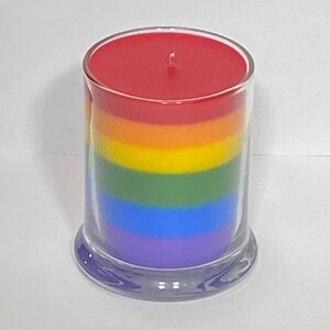 Op de afbeelding: Een regenboog-gekleurde gelaagde kaars in een glazen pot met een rode bovenste laag, oranje, geel, groen, blauw en paarse lagen.
