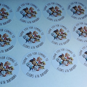 May include: Round white stickers with a Paw Patrol theme. The stickers feature the characters from the show, including Chase, Marshall, Skye, and Rubble. The text on the stickers reads "Thank you for coming to Elisa's 4th Birthday."