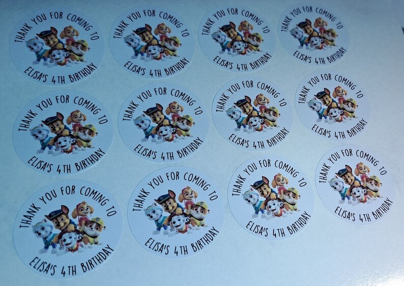 May include: Round white stickers with a Paw Patrol theme. The stickers feature the characters from the show, including Chase, Marshall, Skye, and Rubble. The text on the stickers reads "Thank you for coming to Elisa's 4th Birthday."