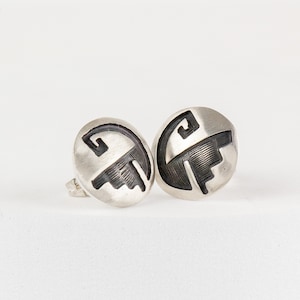 May include: A pair of silver earrings with a black geometric design. The earrings are round and have a post back.